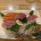 Tanier s čerstvým výberom rôznych druhov sashimi aranžované na rezancoch z bielej repy.